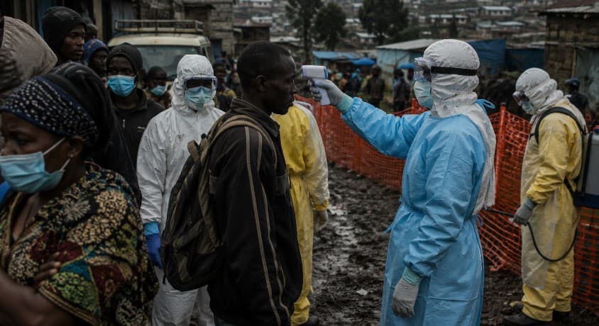 Healthcare workers in full protective suits conduct Ebola screening and emergency medical response operations in a crowded urban area of eastern Democratic Republic of Congo during the 2026 Ebola outbreak crisis.